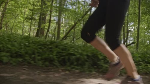Following Shot of Woman's Legs Sprinting Along the Path in the Forest