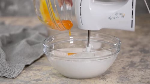 Egg Yolks Poured into Bowl with Mixer Blending