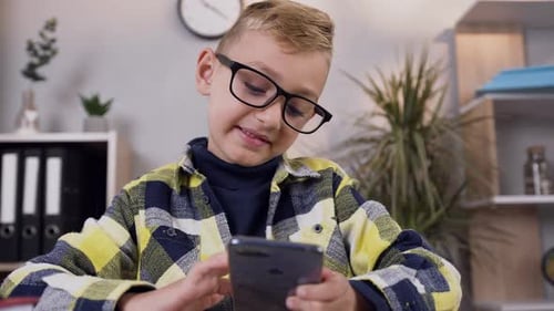 Boy Using Smartphone at Desk