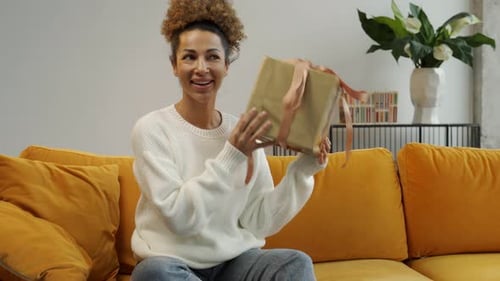 Woman Smiling and Opening Gift at Home