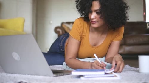 Woman Works On Laptop While Lying on Floor