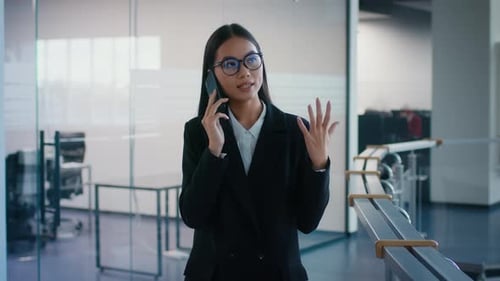 Japanese Businesswoman Talking On Cellphone Walking In Modern Office