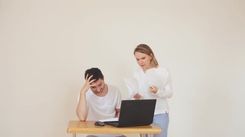 Unglückliches Paar mit Rechnungen und Laptop zu Hause, Steuern zahlen