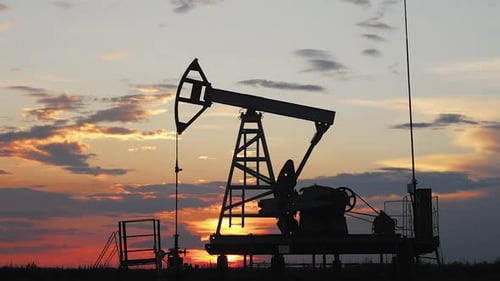 Silhouette Working Oil Pump in Deserted District at Sunset