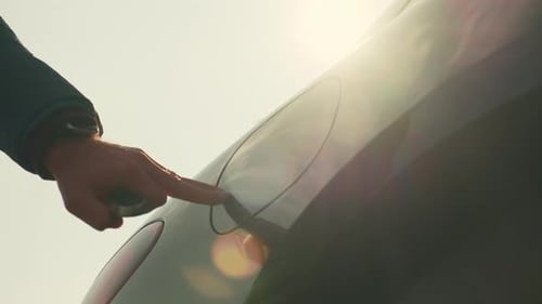 Man Opens Cap Connecting Plug to Electric Car at Sunlight