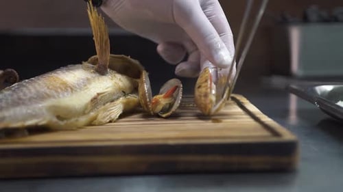 Le chef place des pétoncles rôtis près d'une perche de mer grillée en gros plan