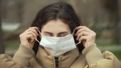 Woman Putting on a Surgical Mask Close Up