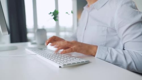 Woman Typing on Keyboard in Bright Office Setting