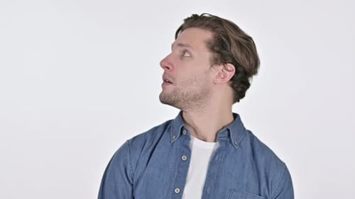 Verängstigter junger Mann schaut sich besorgt auf weißem Hintergrund um