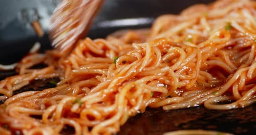 Noodles and Red Sauce Being Stirred in Pan
