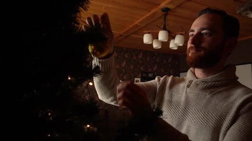Bearded Man Decorating a Christmas Tree Indoors