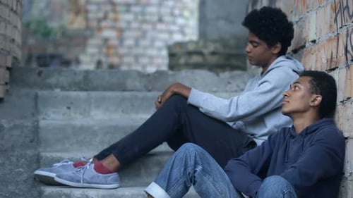 Armer einsamer Teenager schaut einander sitzend verlassenes Gebäude, Schwierigkeiten