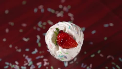 Sirope rojo vertido en Cámara lenta sobre el pastel con crema y fresa