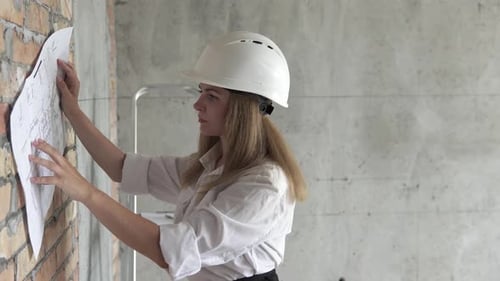 Die Ingenieurin überprüft die Zeichnungen in der Wohnung des geplanten Hauses.