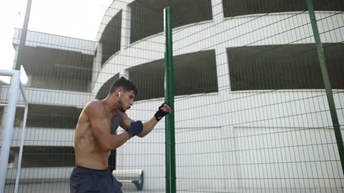 Shirtless Man Practicing Boxing in Urban Setting