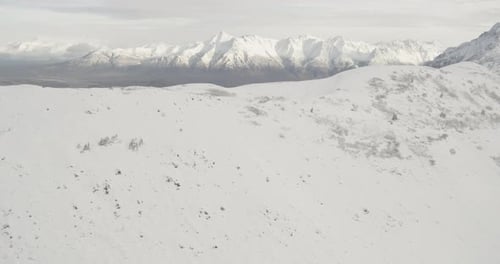 Aerial helicopter shot of frozen Alaskan river, tilt up to reveal mountains, frozen forests, drone f