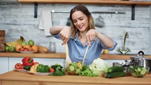 Smiling Woman Mixing Fresh Salad in Bright Kitchen