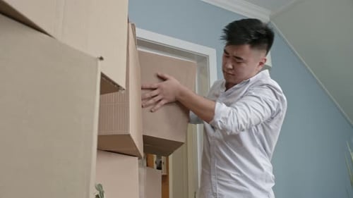Man stacks cardboard boxes indoors