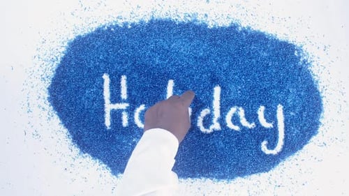 Creative Hand Writes Holiday Over Blue Particles