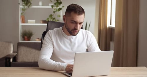 Stressed Man Working at Laptop in Home Office