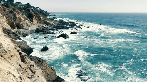 Rocky coast of the Pacific Ocean. Sea waves crash against the rocky coast. A sunny day and a beautif