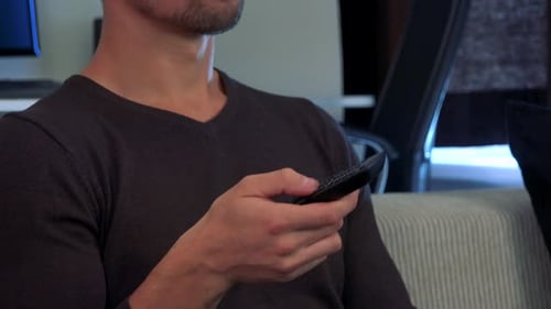 A Man Sits on a Couch and Clicks with a Controller