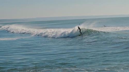Surfer riding a big blue wave of the Atlantic Ocean on a beautiful sunny day