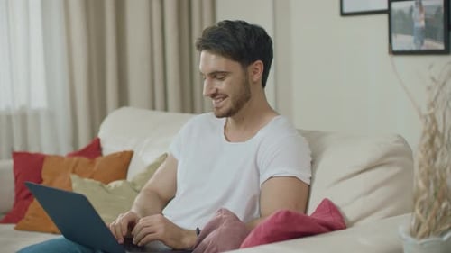 Man Working on Laptop While Relaxing on Sofa