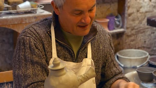 Potter Shaping Clay Jug in Workshop