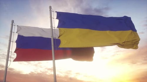 Waving Russian and Ukrainian Flags Against a Sunset Sky