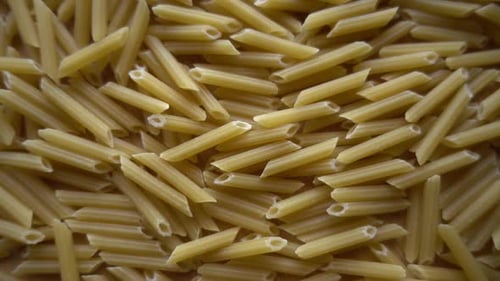 Dry Penne Pasta Close Up on Light Wood