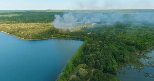 Der große Rauch von Waldbränden oder Waldbränden brennt Bäume und trockenes Gras in der Nähe des Sees