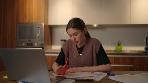 A Pensive Woman Looks at the Documents and the Graphs on the Table Make Notes in the Papers
