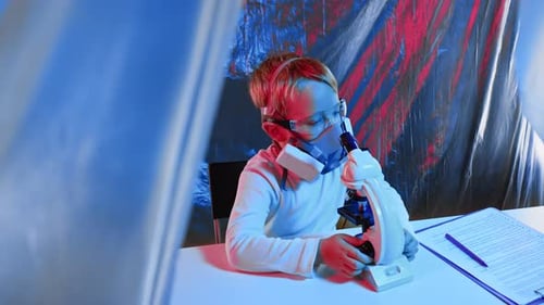 Ein kleiner Junge mit Schutzmaske und Brille sitzt in einem Forschungslabor.