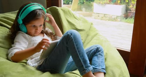 Girl Relaxing with Tablet Wearing Headphones Indoors