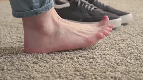 Füße und Sneaker für Damen auf dem Teppich Slow Mo