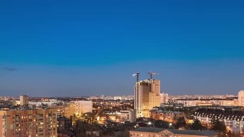 El paisaje urbano nocturno y las grandes grúas construyen edificios de varios pisos