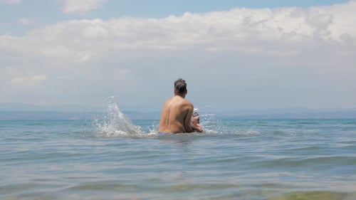 Happy European Family Playing at the Sea. Dad and Little Son Play and Enjoy the Sea Water on the