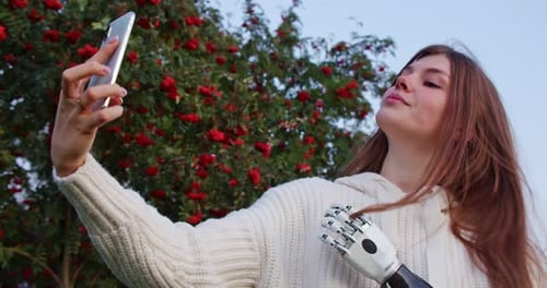 Young Woman With Prosthetic Arm Taking Selfie Outdoors
