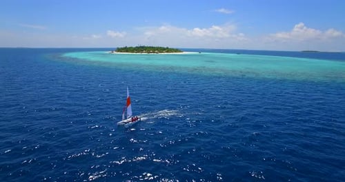 Aerial drone view of a man and woman sailing on a boat to a tropical island