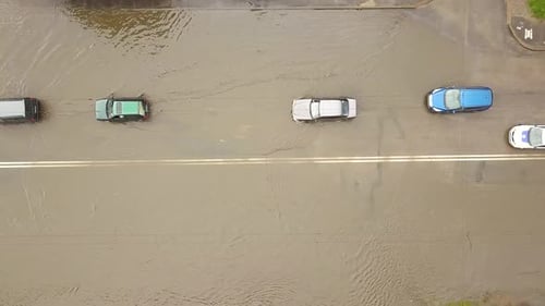 Aerial view of traffic cars driving on flooded road with rain water.