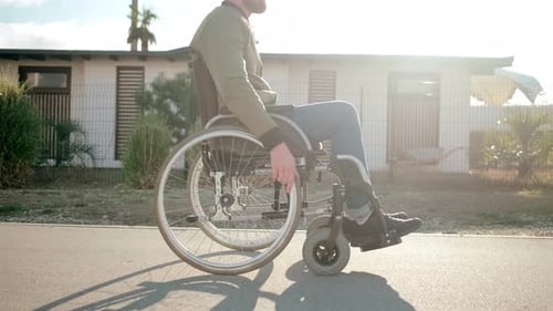 Adult in Wheelchair Moving Along Paved Path