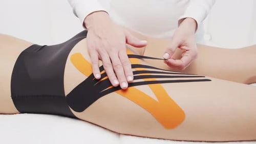Applying Kinesiology Tape to Woman's Leg Close Up