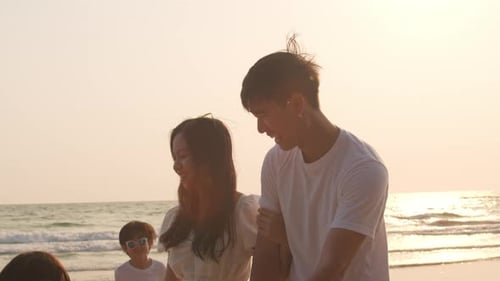 Dad, mom and kid relax playing together near sea when sunset.