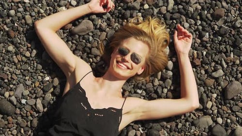 Smiling Woman Relaxing on Rocky Beach, Stone Eyes