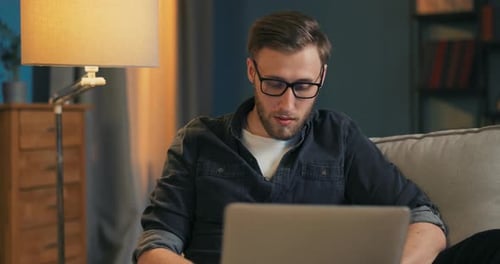 Man Relaxing on Couch Using Laptop at Home