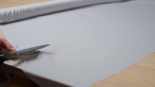 Cutting Grey Cloth from Roll with Scissors
