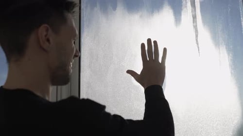 Young Adult Draws on Frosted Window in Winter