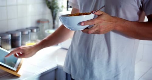 Woman using digital tablet while having breakfast