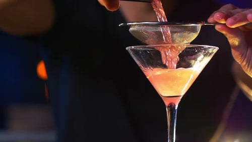 Adult Bartender Pouring Cocktail into Stemmed Glass